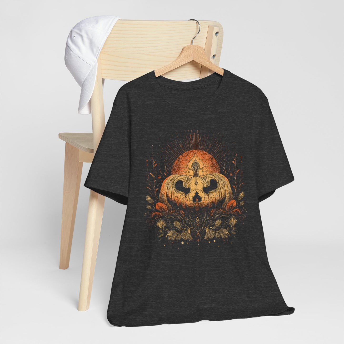Black t-shirt with a pumpkin design on a wooden chair against a white background