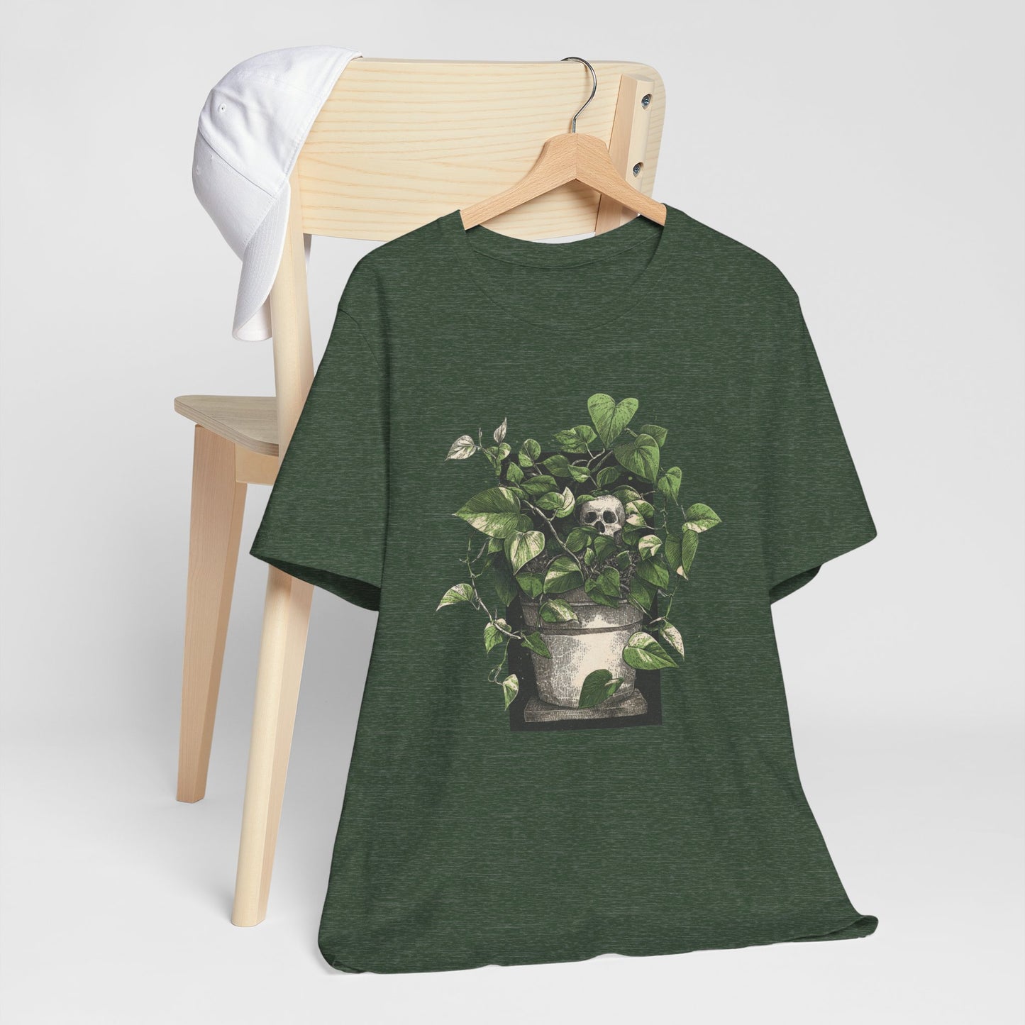 Green t-shirt with a skull and leaves design on a wooden chair against a white background