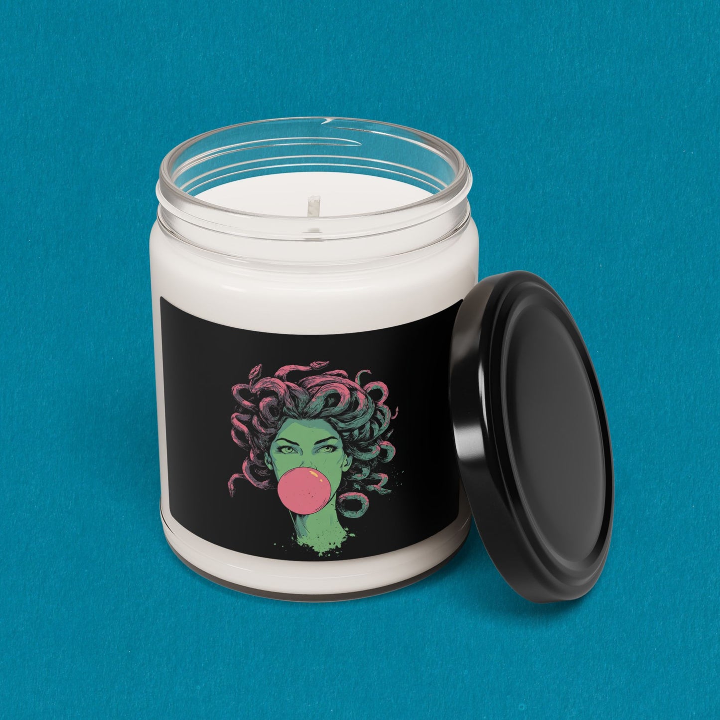 Candle in a jar with a colorful design on a black label against a blue background