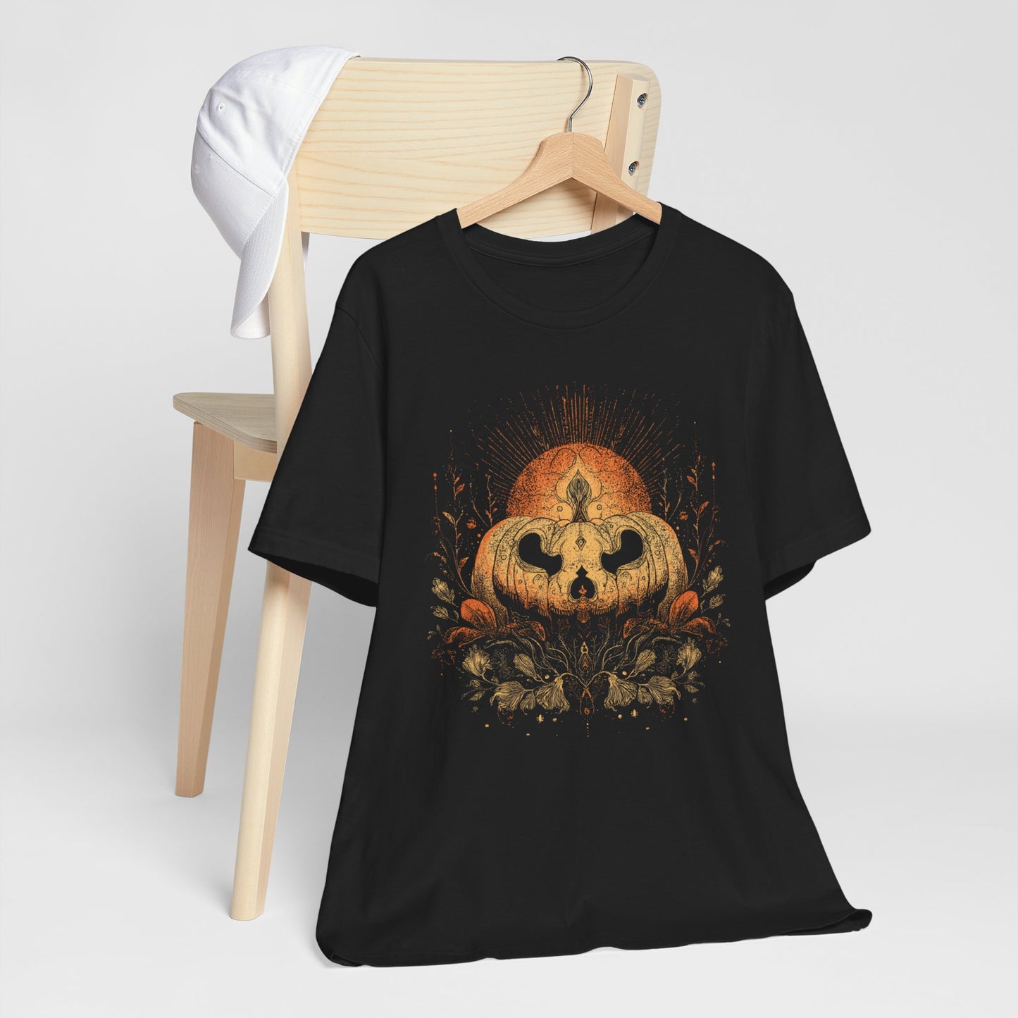 Black t-shirt with a pumpkin design on a wooden chair against a white background