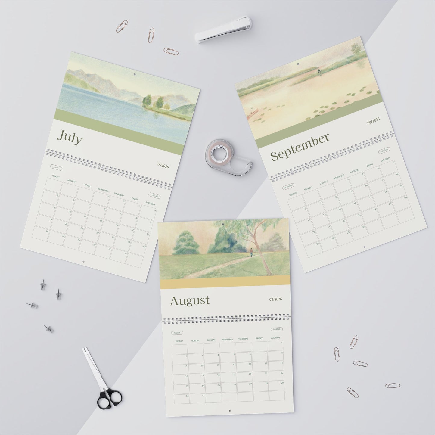 Three scenic calendars for July, August, and September on a light gray background with office supplies.