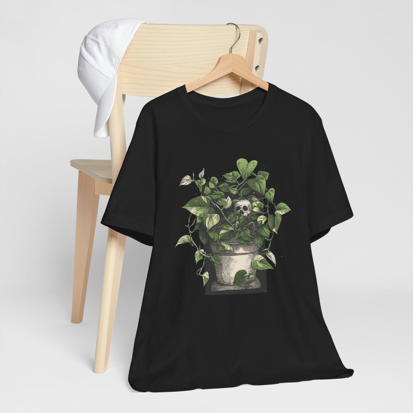 Black t-shirt with a plant and skull design on a hanger against a white background