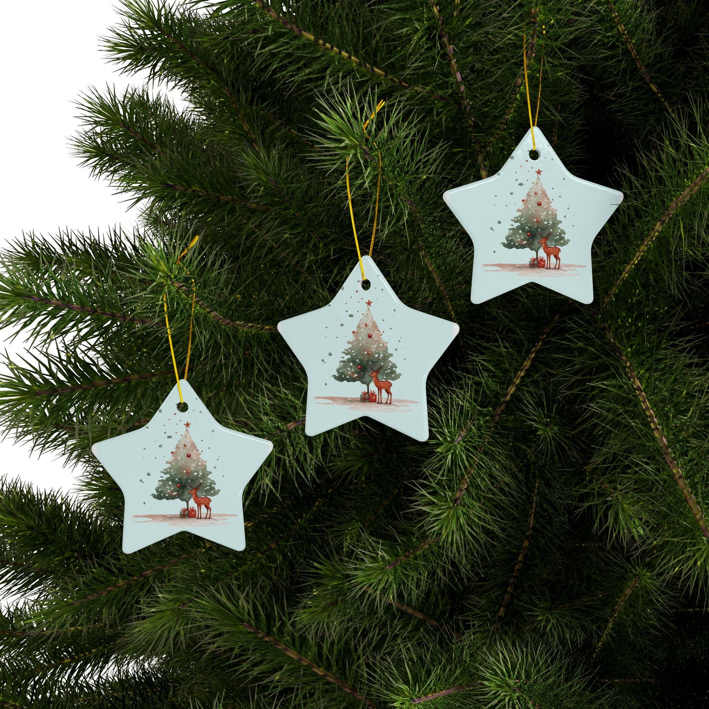 Star-shaped Christmas tree ornaments with reindeer and trees on a green pine branch.