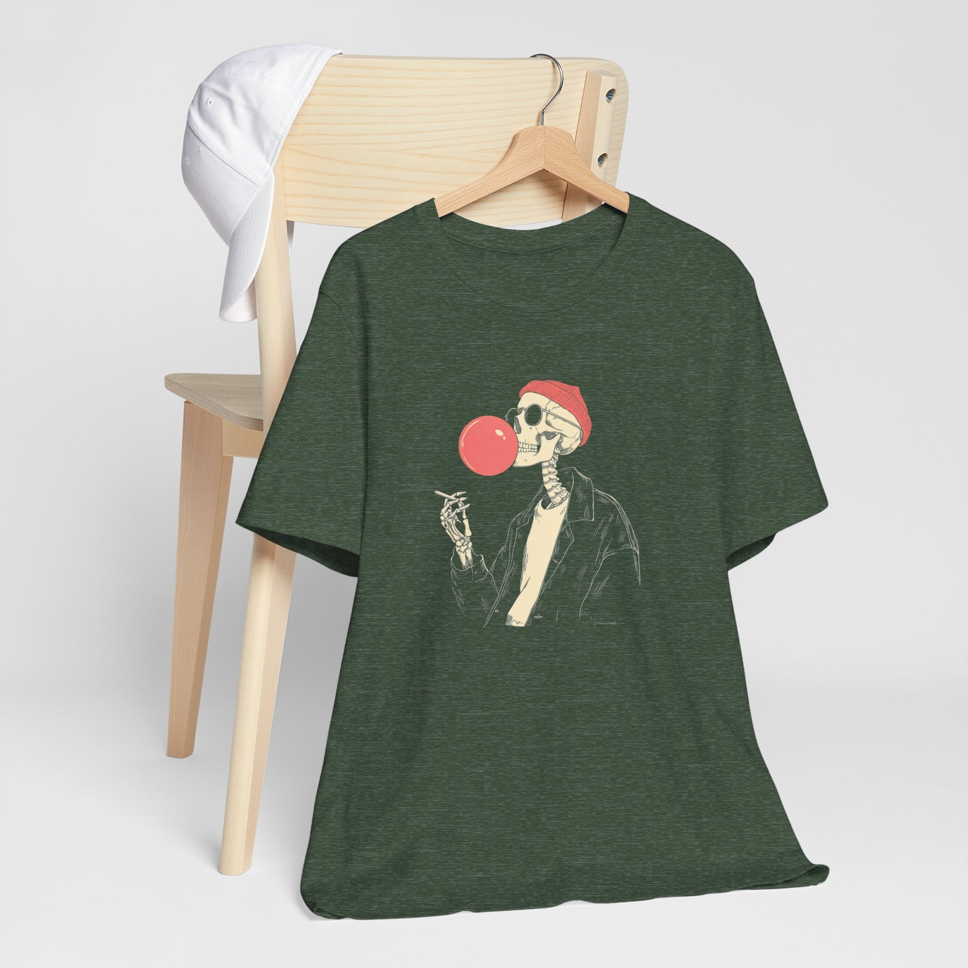 Green t-shirt with a skeleton design blowing a red bubblegum bubble, hanging on a wooden chair.