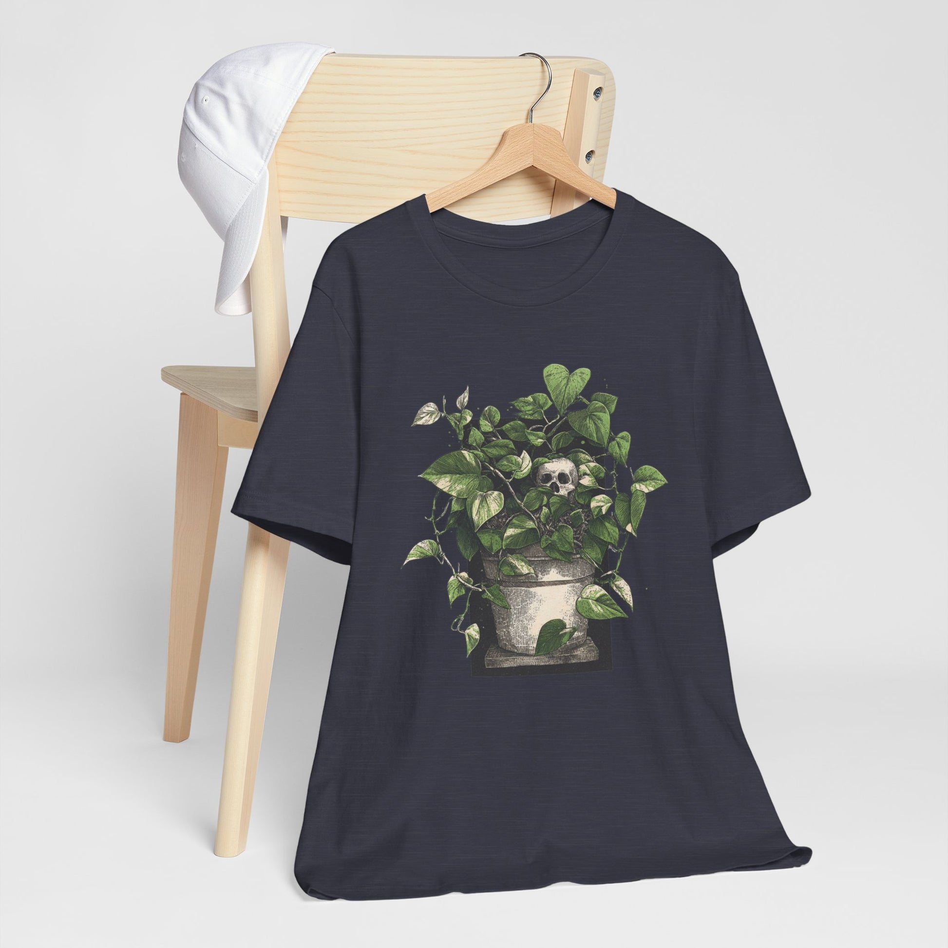 Black t-shirt with a plant and skull design on a wooden chair against a white background