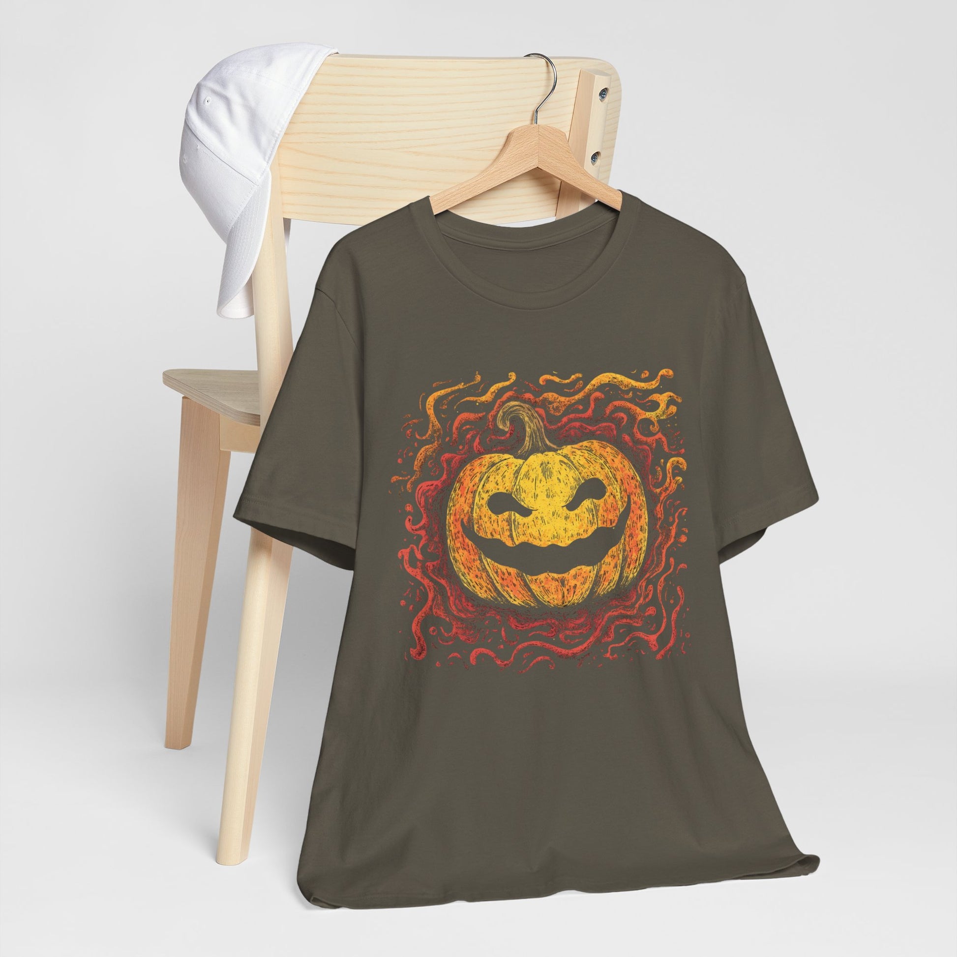 Brown t-shirt with a Halloween pumpkin design on a wooden chair against a white background