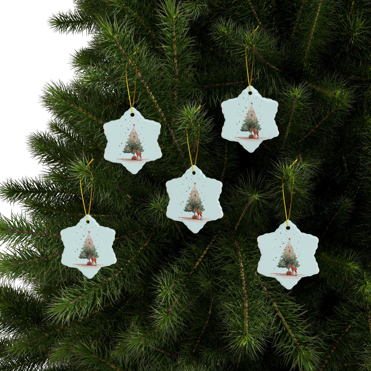 Star-shaped Christmas tree ornaments with a tree design hanging on a green pine branch.