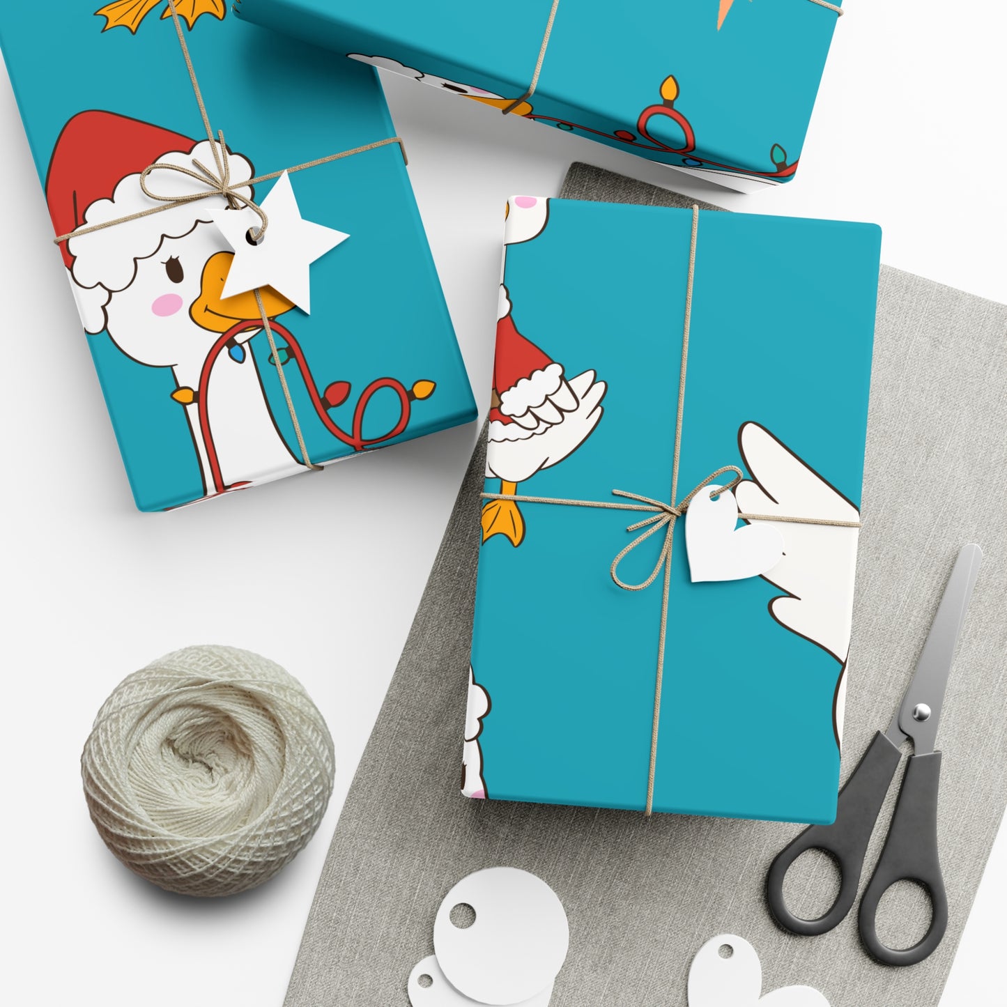 Turquoise gift boxes with cartoon duck design, yarn, and scissors on a white surface