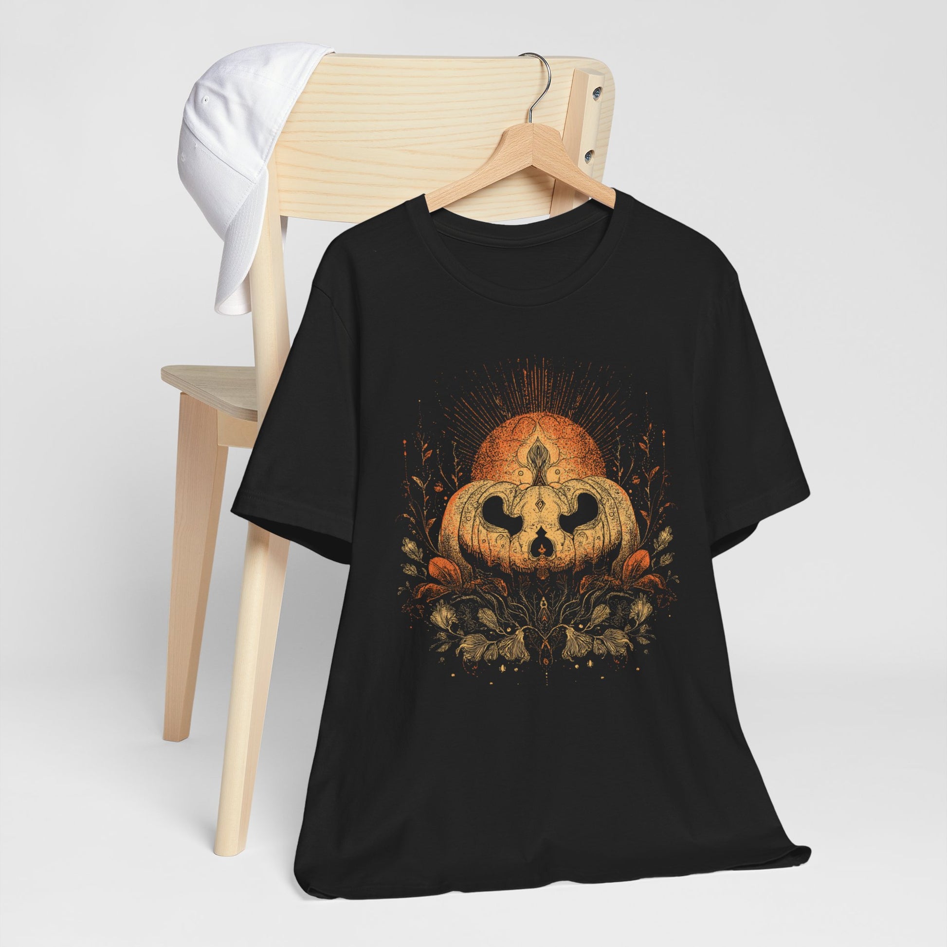 Black t-shirt with a pumpkin design on a wooden chair against a white background