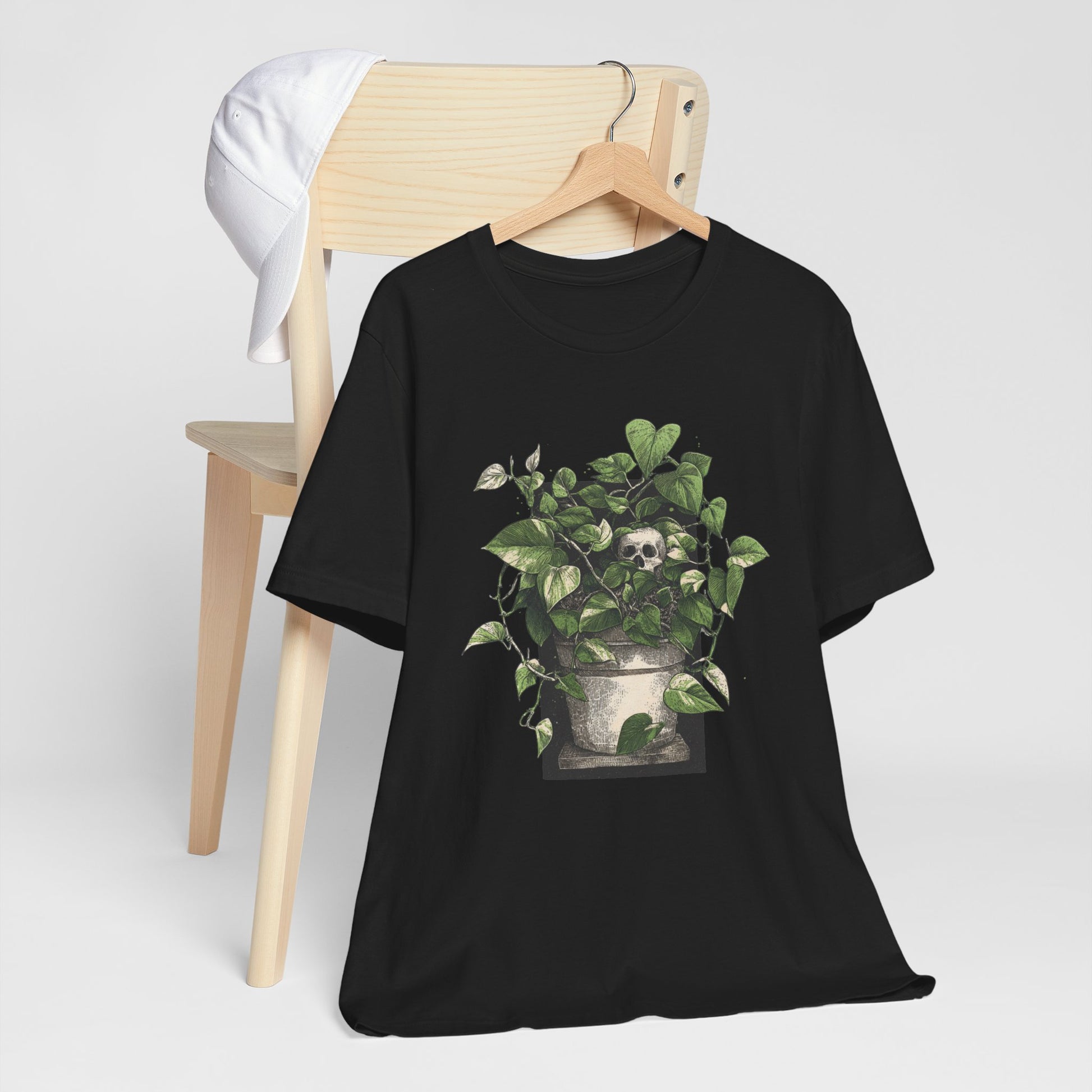 Black t-shirt with a plant and skull design on a hanger against a white background