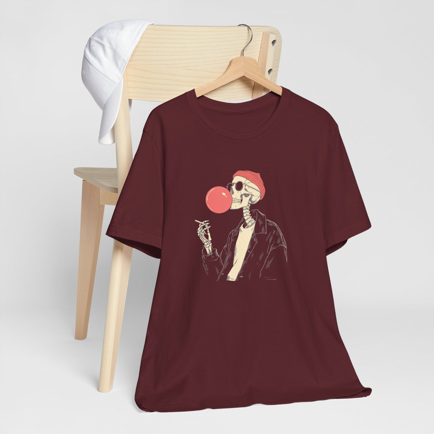 Maroon t-shirt with skeleton design on a wooden chair against a white background