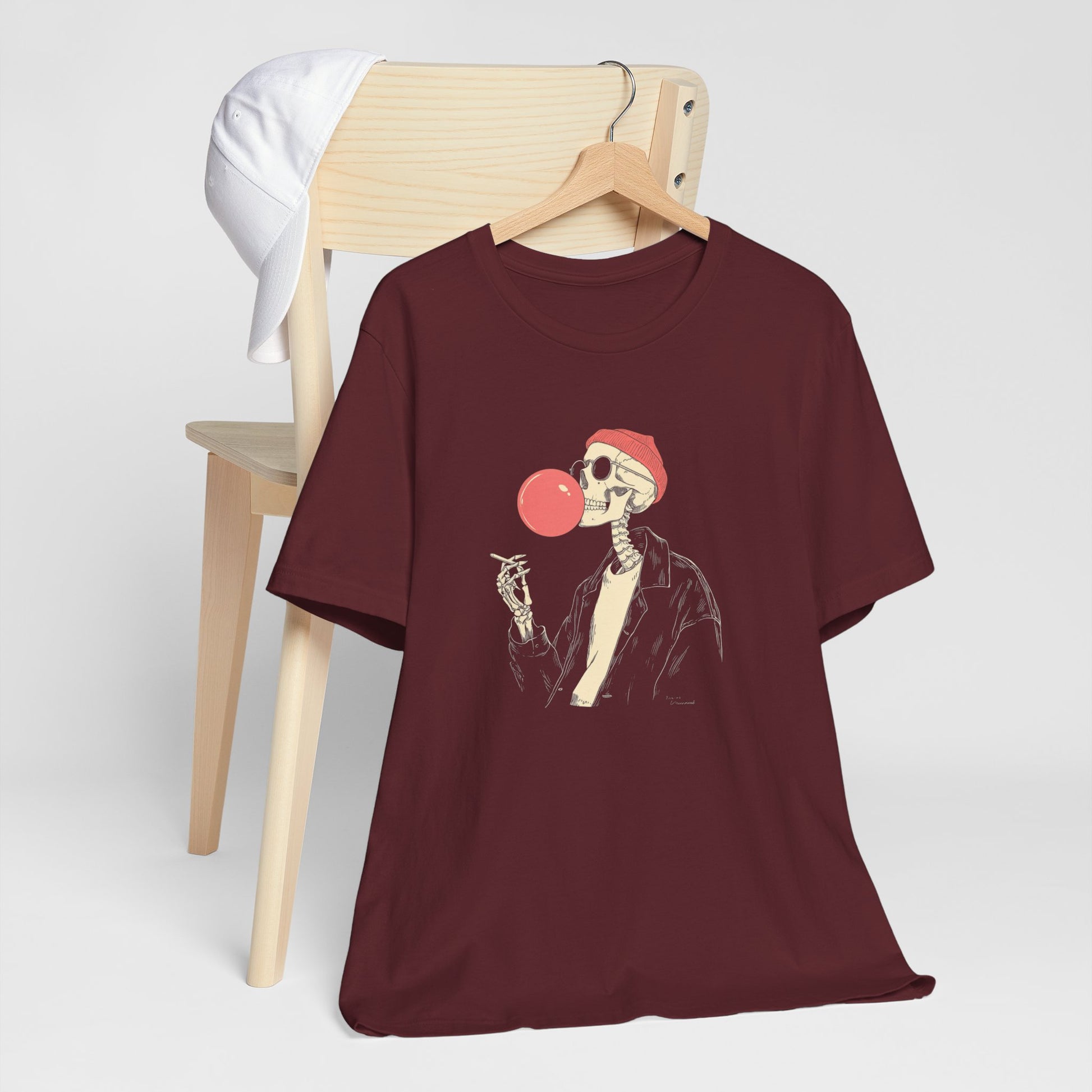 Maroon t-shirt with skeleton design on a wooden chair against a white background