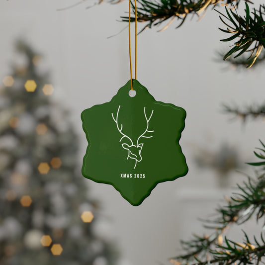 Green Christmas ornament with deer design and 'XMAS 2023' text, hanging on a tree branch.